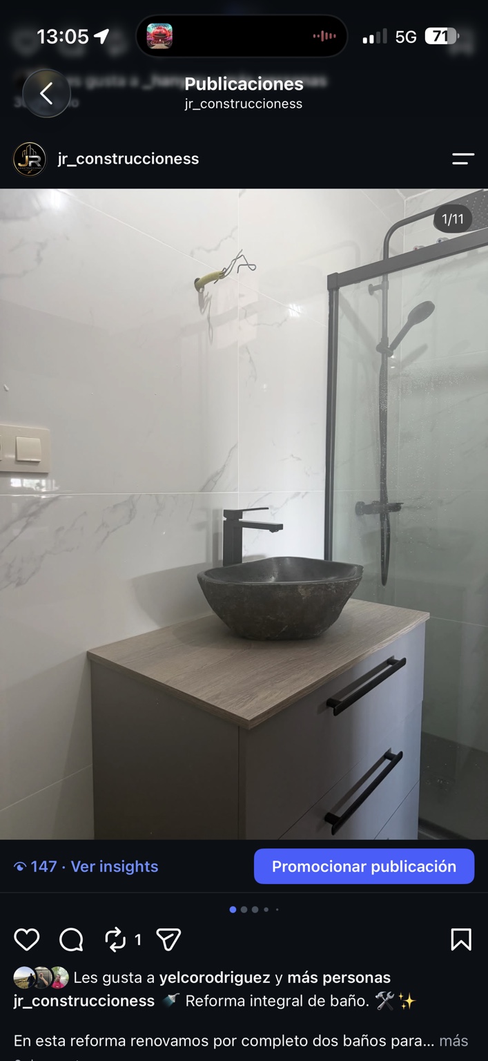Baño en fase de montaje con lavabo oscuro, grifería negra y revestimiento claro